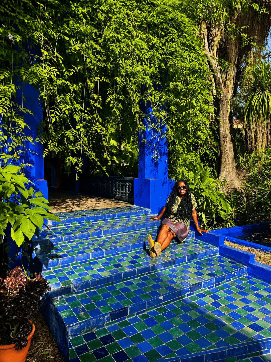 Woman resting on a tiled garden staircase surrounded by lush foliage